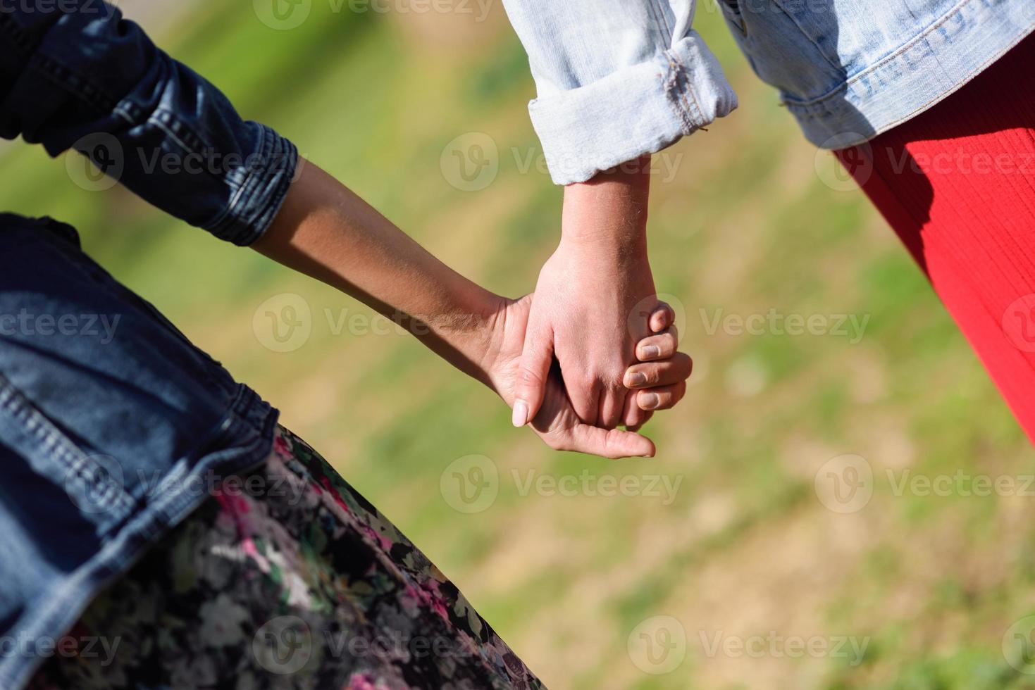 Two young women in walking holding her hands in urban park. photo