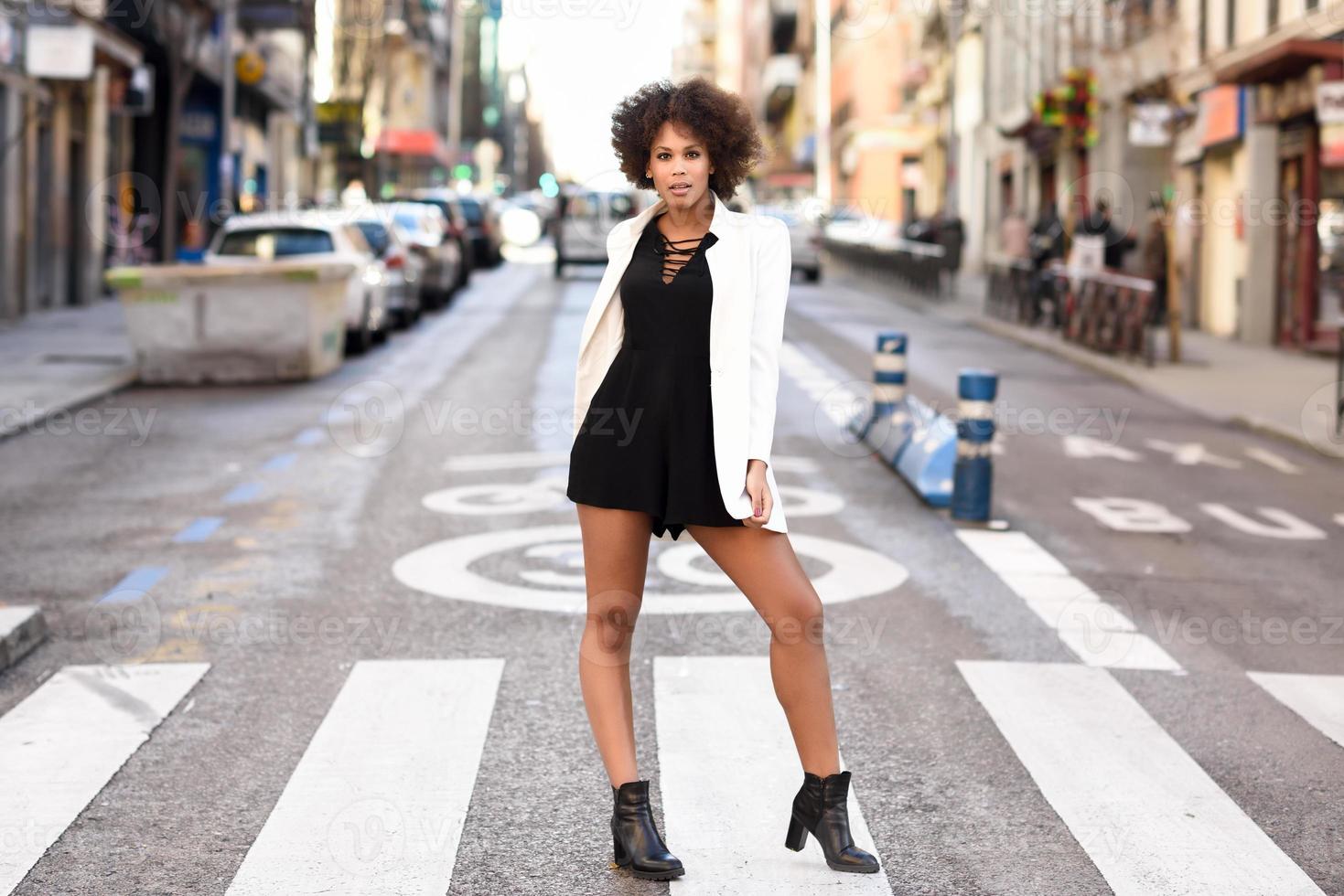 joven mujer negra con peinado afro de pie en el fondo urbano foto