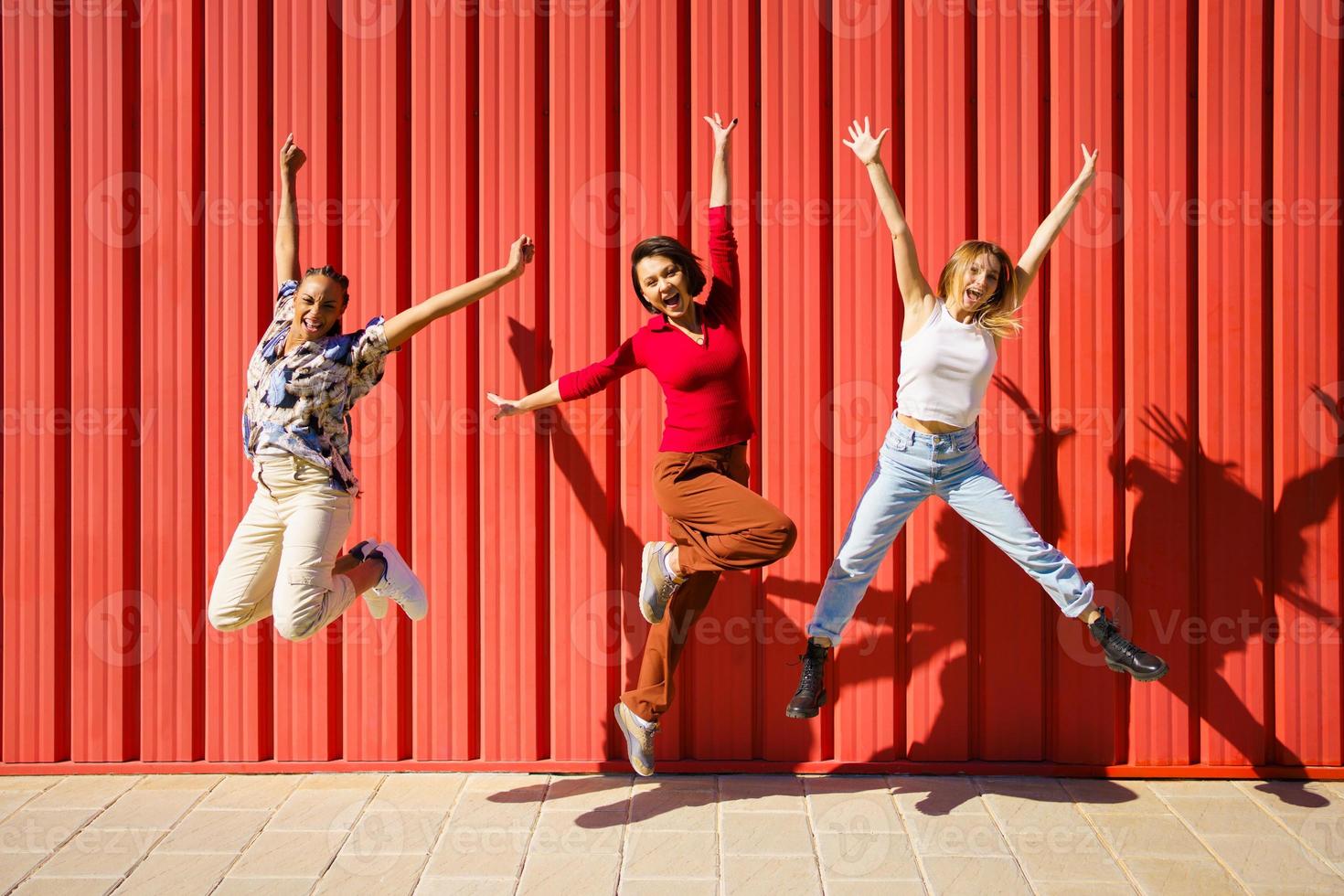 alegres mujeres diversas saltando cerca de la pared foto