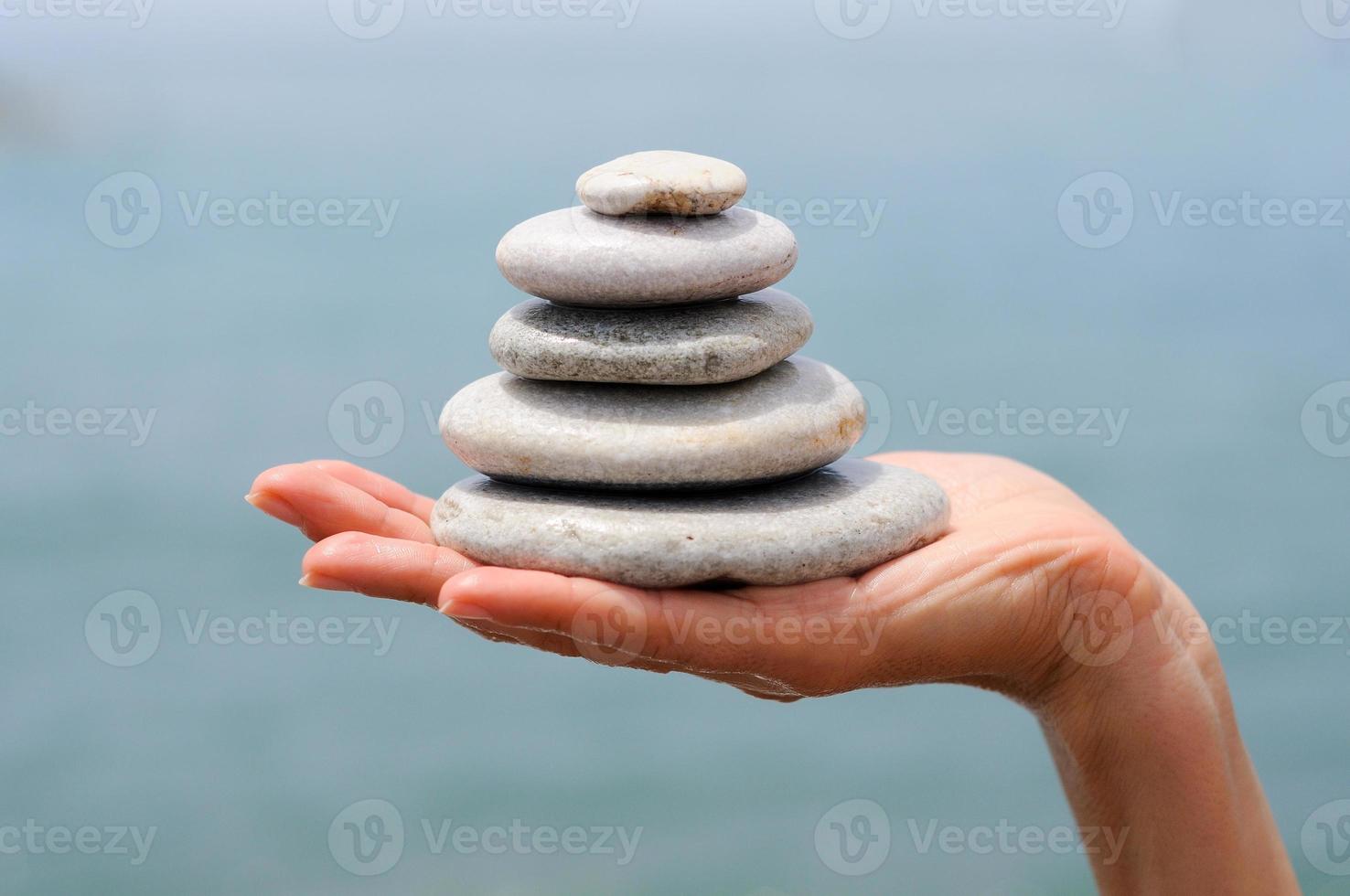 Gravel pile in woman's hands with sea background photo