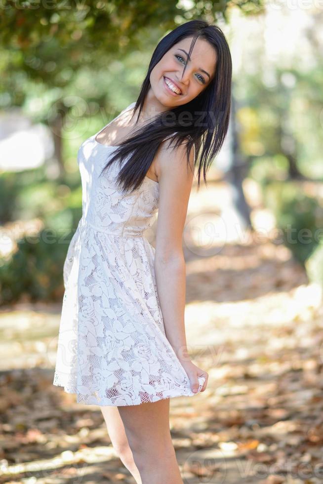 Young woman wearing white dress in urban park photo