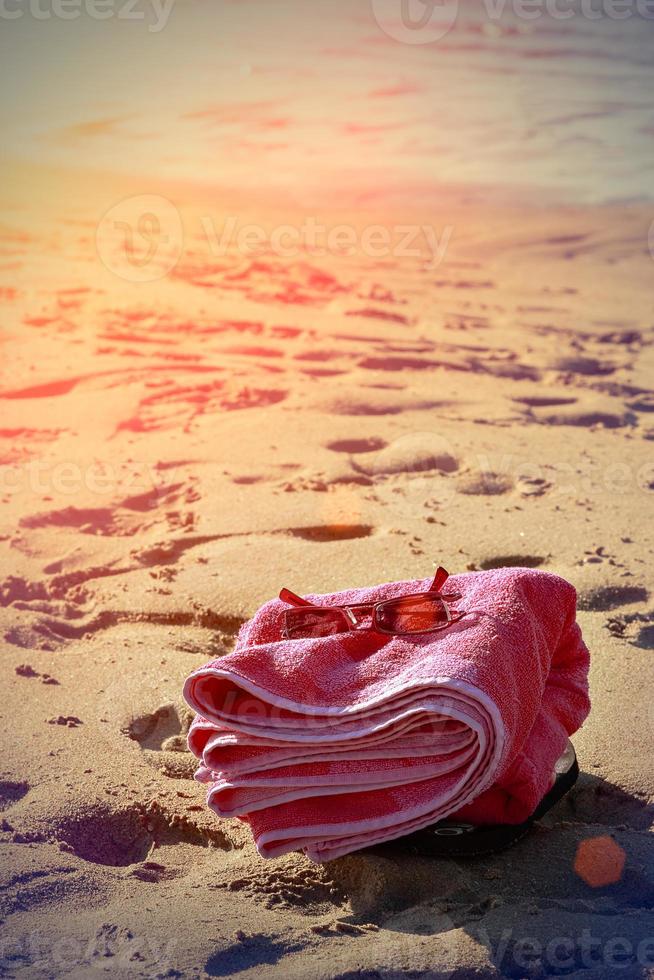 Beach towel in the sand with sunglasses in vintage style. Vertical image. photo