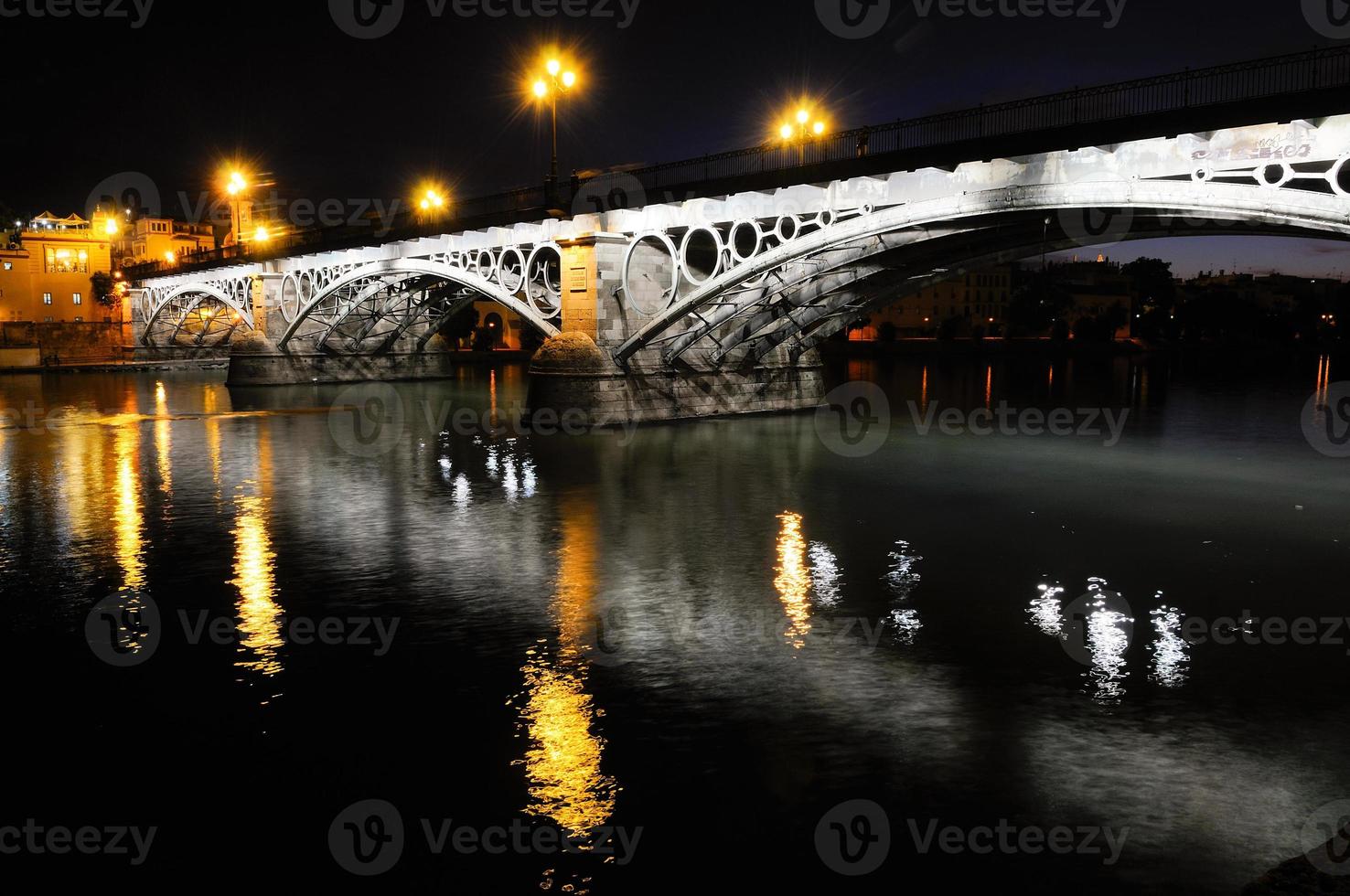 puente de triana sobre el río guadalquivir al atardecer con reflejos del río foto