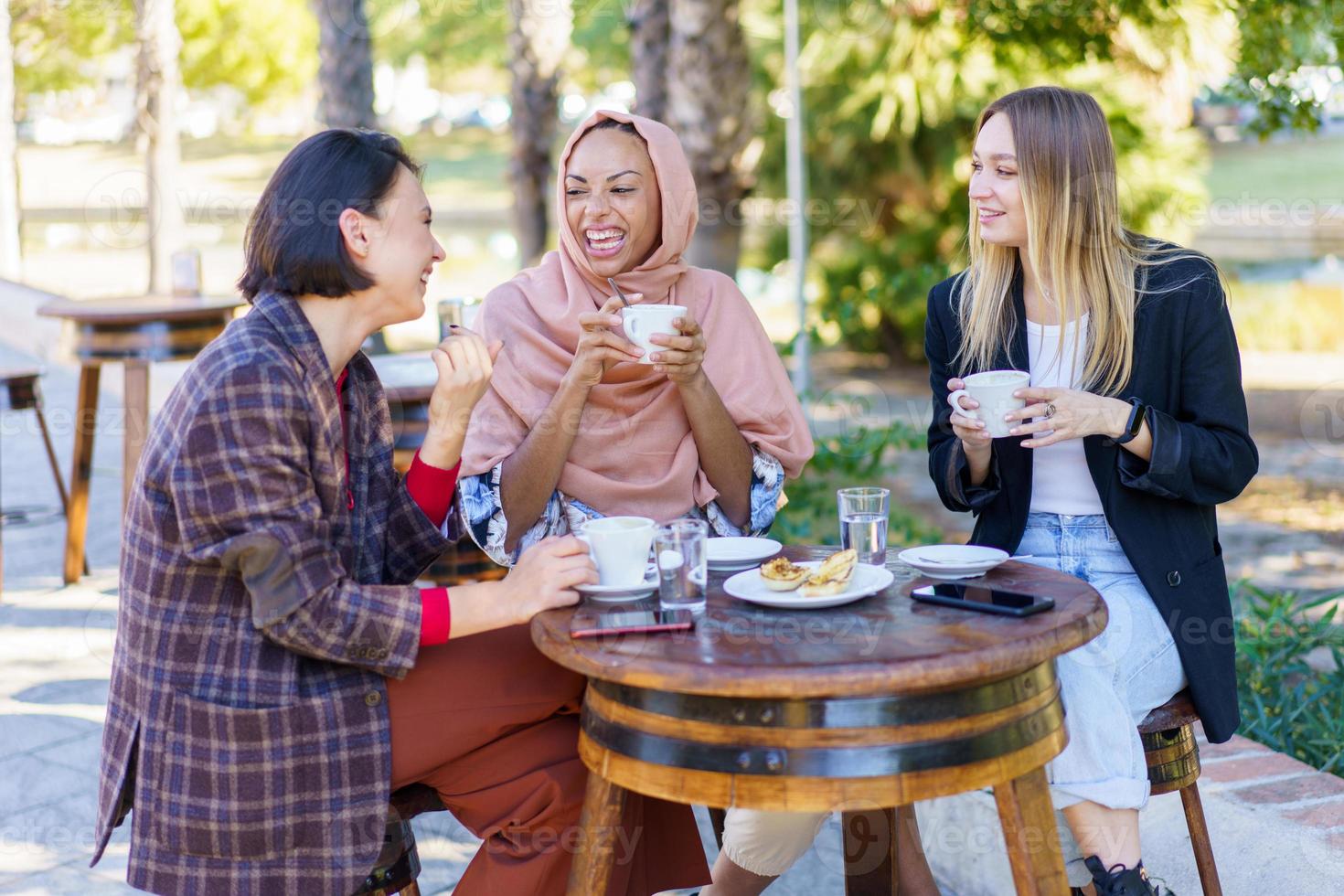 Delighted diverse women drinking coffee photo