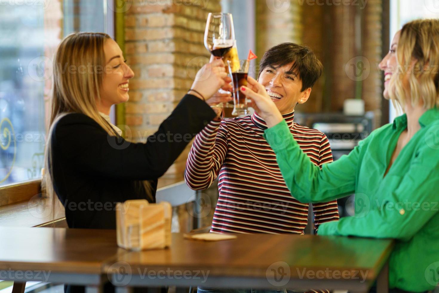 Excited women proposing toast near pub window photo