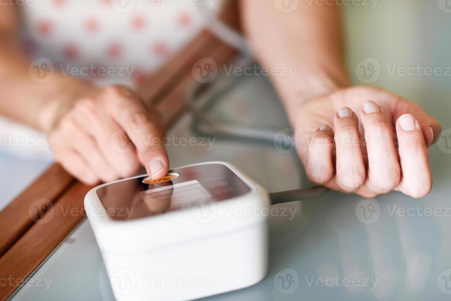 Woman measuring her own blood pressure at home. photo