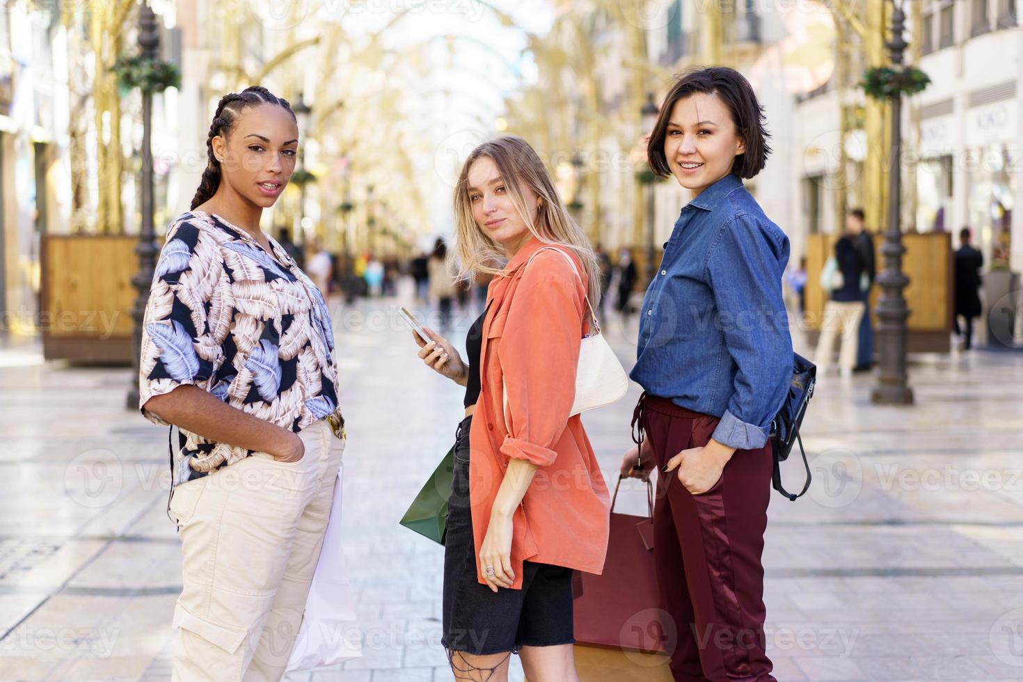 Multiracial female friends standing on city street with purchases photo