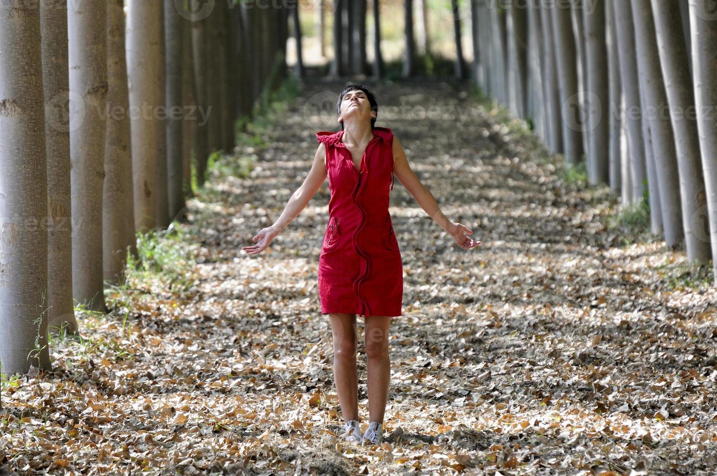 mujer vestida de rojo, meditando en el bosque foto