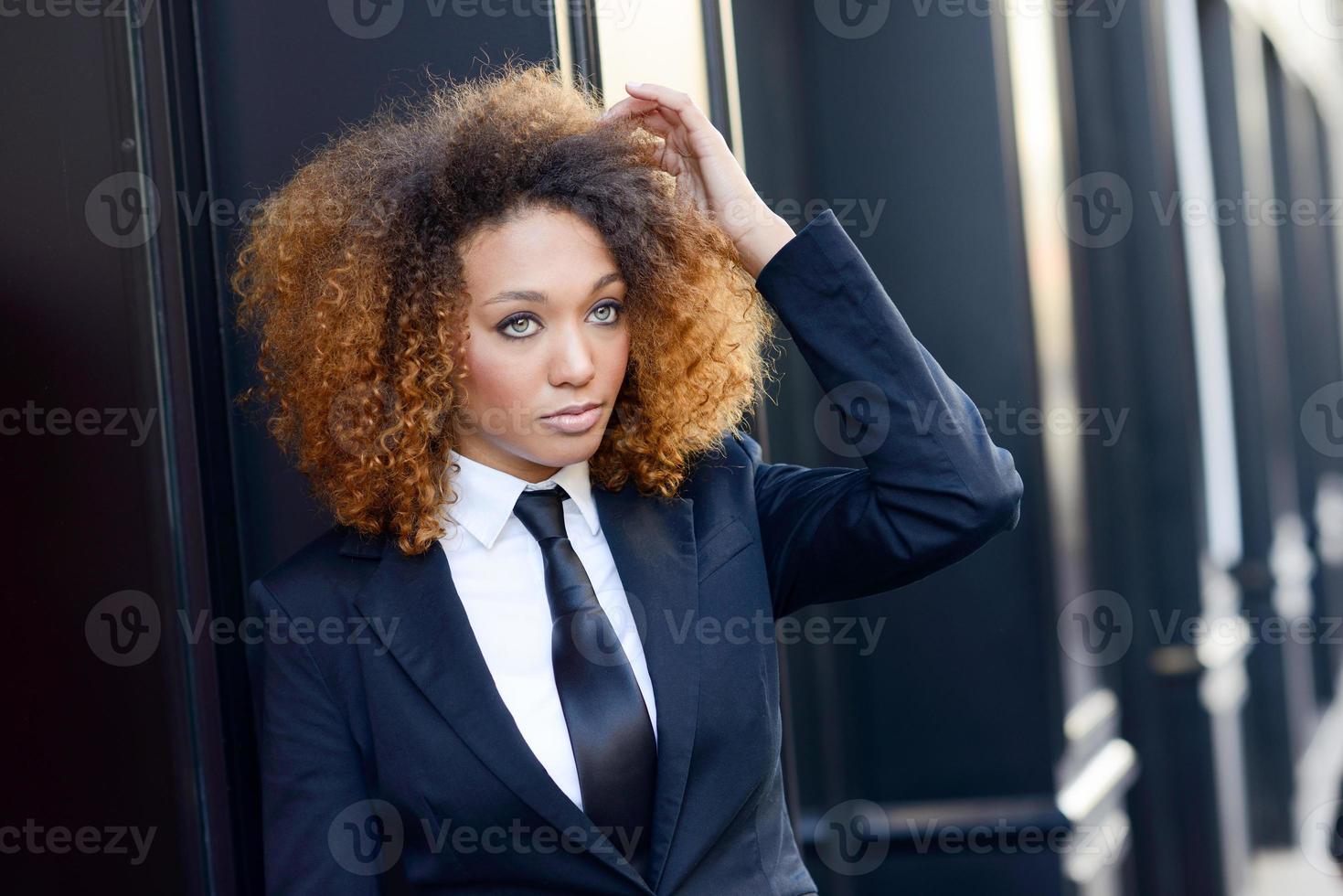 Black businesswoman wearing suit and tie in urban background photo