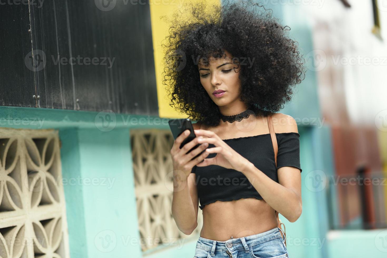 Black woman afro hair on the street holding a smartphone photo