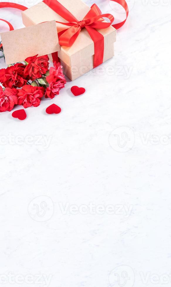 May mothers day concept handmade giftbox idea wishes photography - Beautiful blooming carnations with red ribbon bow box isolated on modern marble desk, close up, copy space, mock up photo