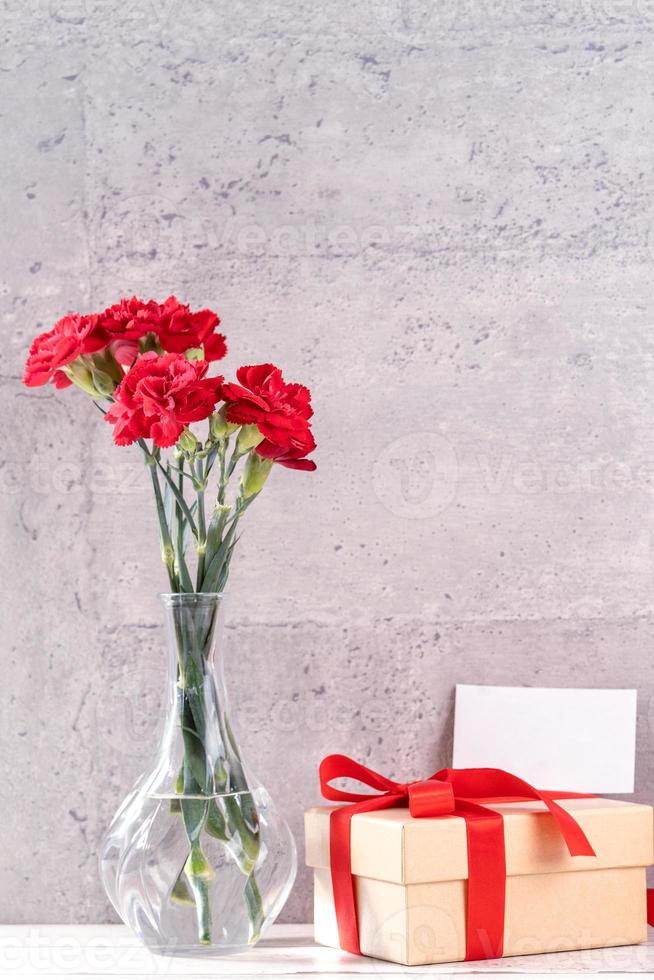 May mothers day handmade giftbox wishes photography - Beautiful blooming carnations with red ribbon box isolated on fair-faced gray background desk, close up, copy space, mock up photo