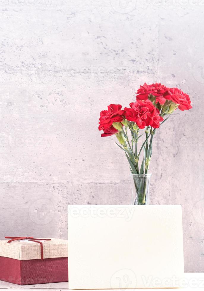 May mothers day handmade giftbox wishes photography - Beautiful blooming carnations with red ribbon box isolated on fair-faced gray background desk, close up, copy space, mock up photo