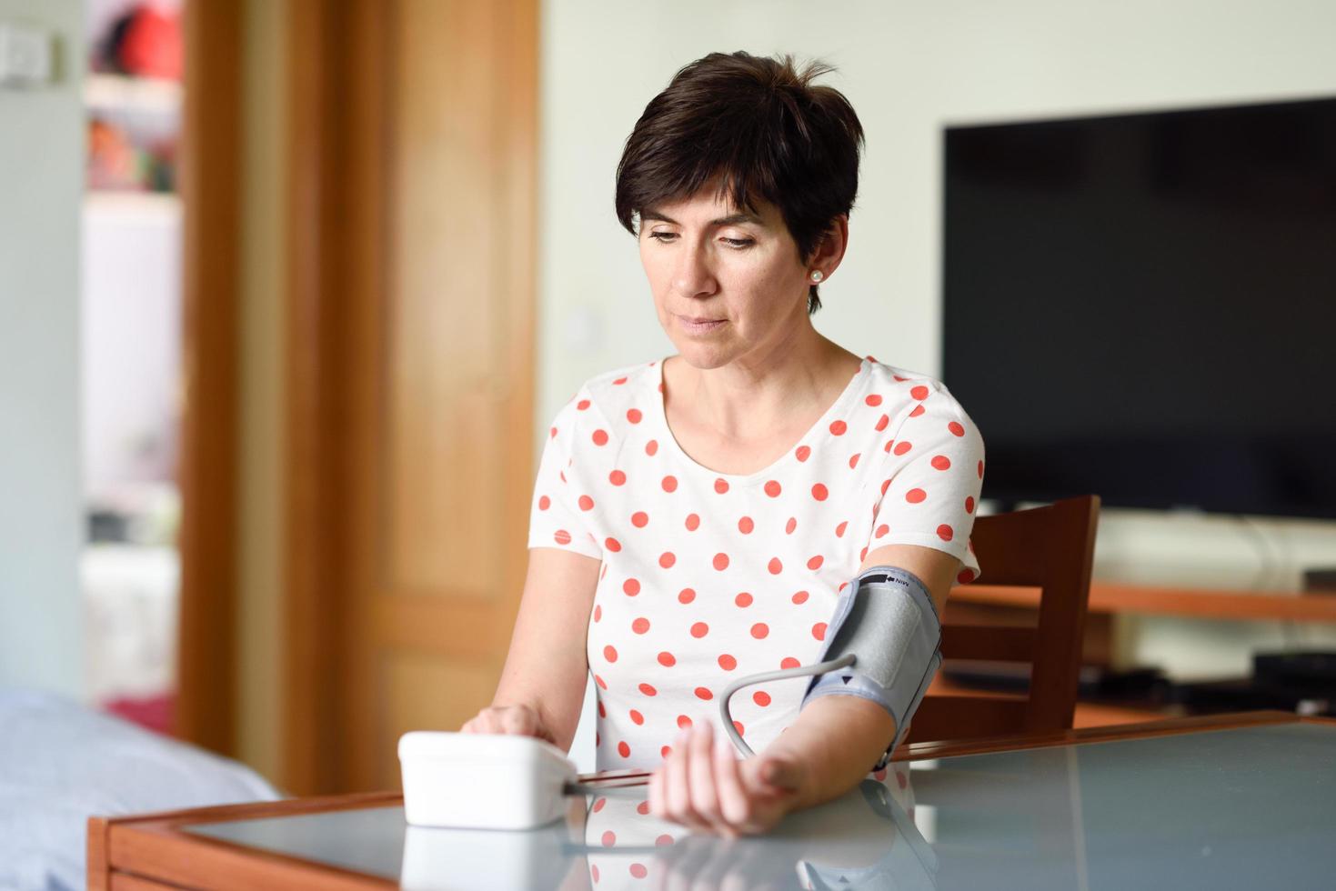 Woman measuring her own blood pressure at home. photo