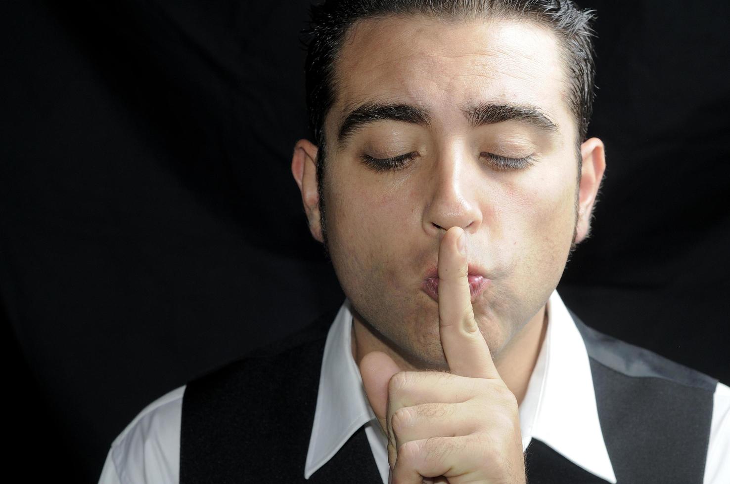 Man asking for silence with his finger over his mouth photo