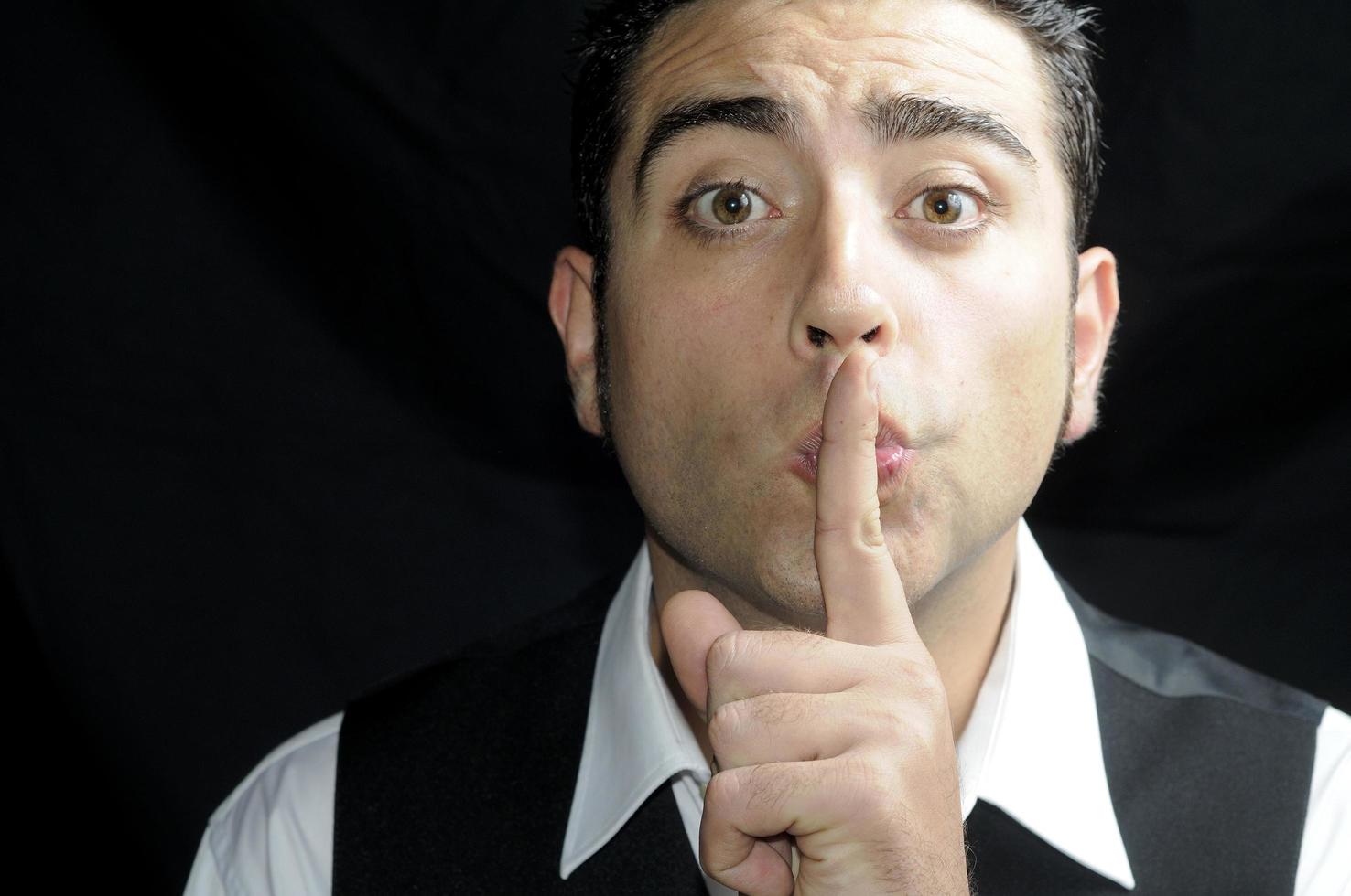 Man asking for silence with his finger over his mouth photo