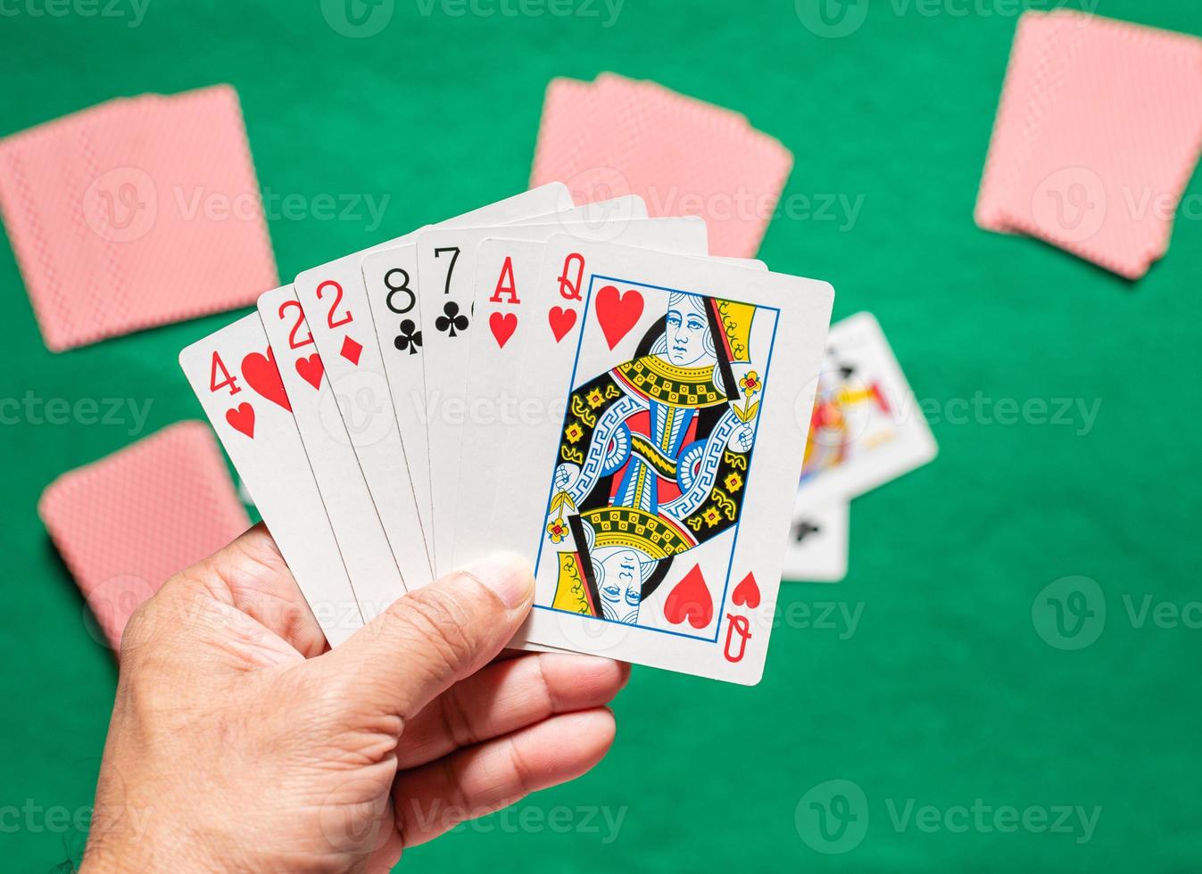 Closeup, man's hand holding cards in rummy play also called card game. Blurred background photo