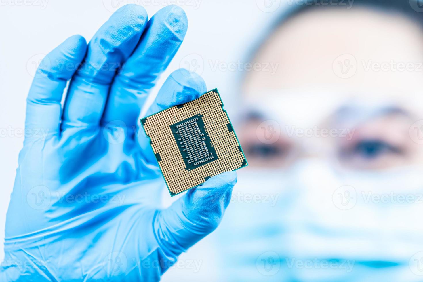 A female engineer working in a lab wearing protective goggles and gloves holds the new processor in her hands and examines it. Scientist holding chipset in laboratory Computer concepts, hardware, fix photo