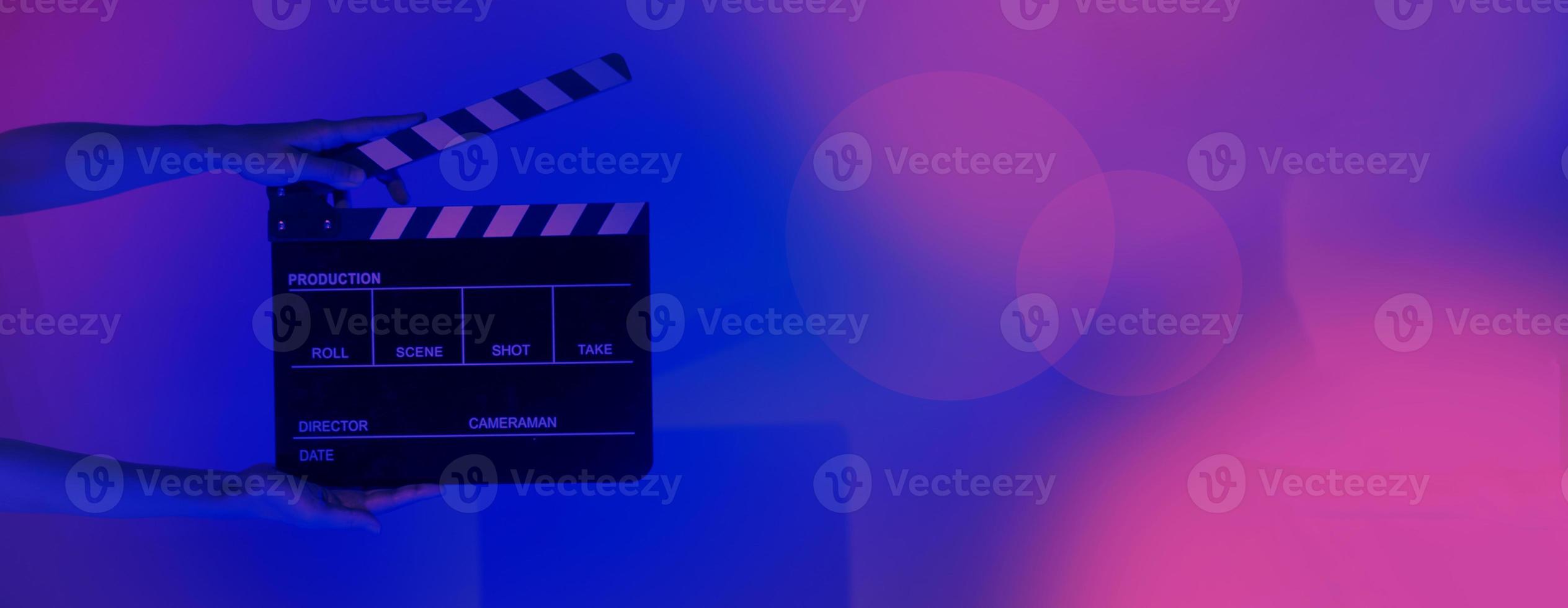 Hand holds empty film making clapperboard on color background in studio photo