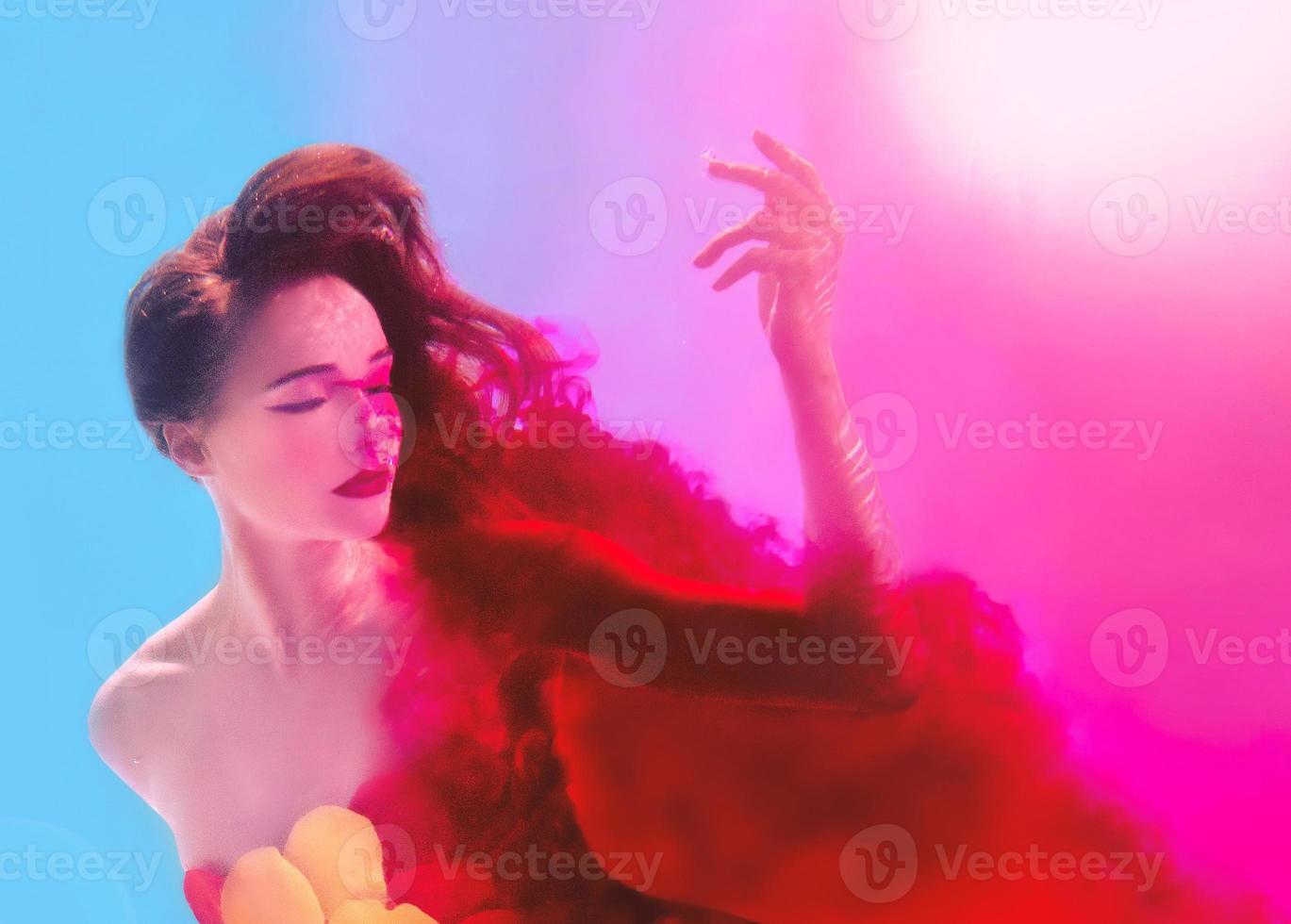 Surreal portrait of young attractive woman with air bubbles underwater in colorful water with ink in the swimming pool photo