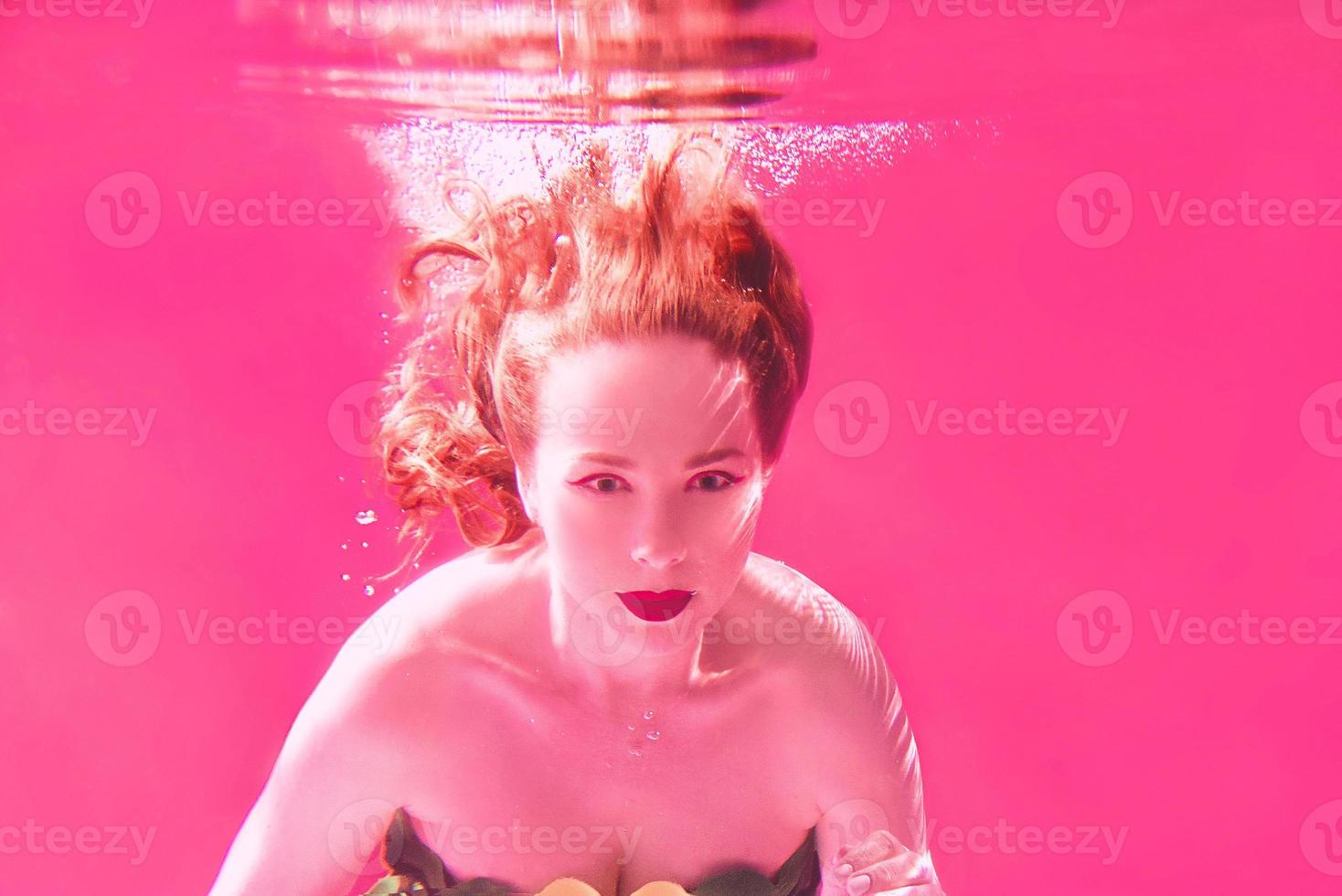 Surreal portrait of young attractive woman with air bubbles underwater in colorful water with ink in the swimming pool photo