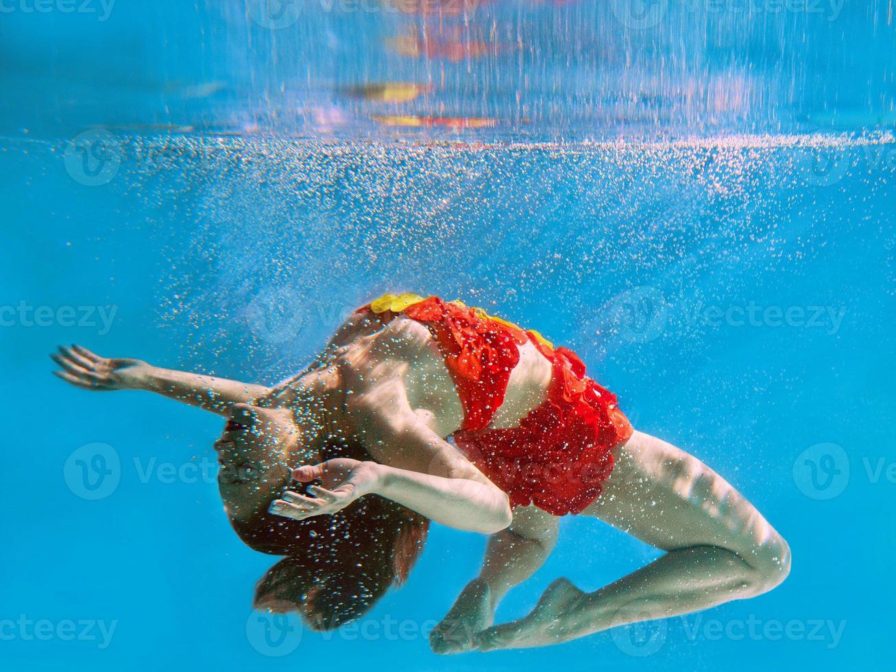 unbelievable, surreal, incredible, amazing underwater portrait of slim, fit woman in bright orange swimming suit photo