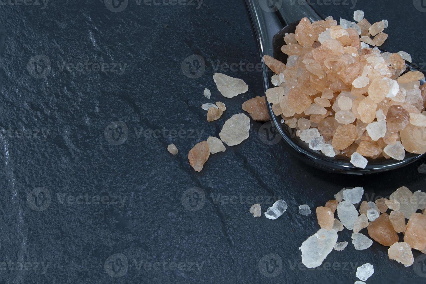 Pink Himalayan salt on a black rock ground. photo