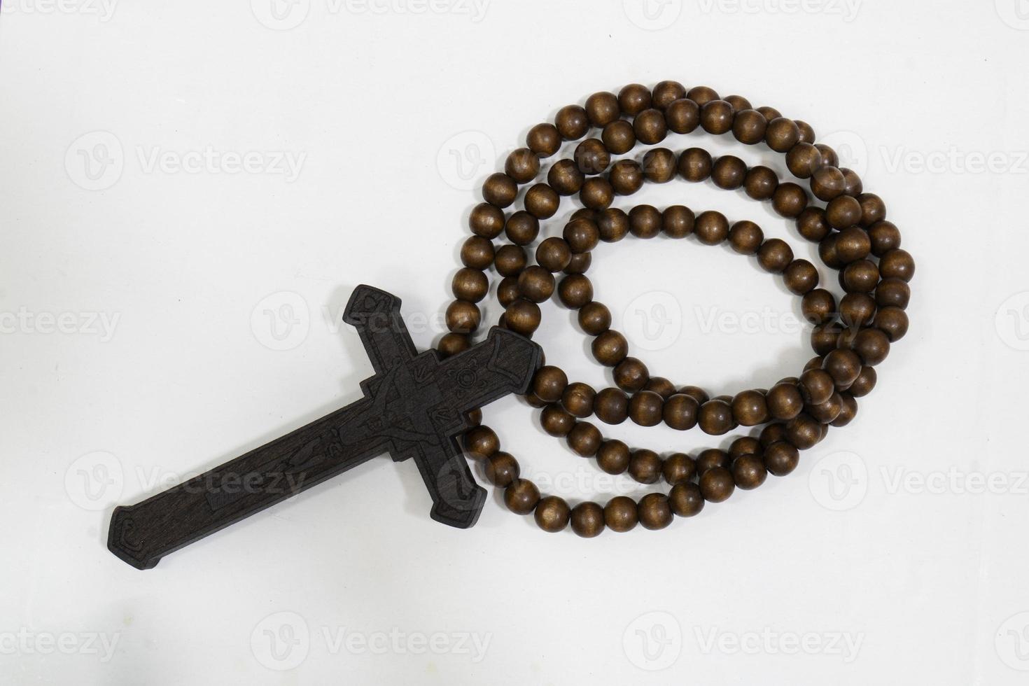 rosary beads with cross made of black wood on a white background, selected focus on christ, narrow depth of field. photo
