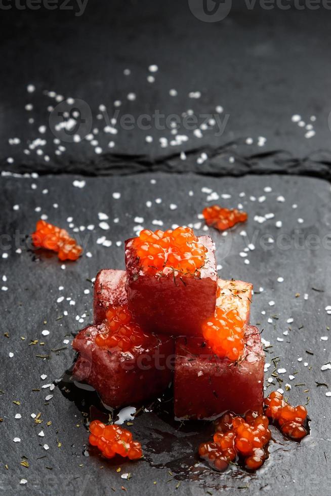 Tuna sashimi dipped in soy sauce with salmon roe, thick salt and dill on slate stone. Raw fish in traditional Japanese style. Vertical image. photo