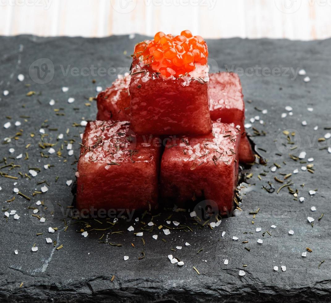 Tuna sashimi dipped in soy sauce with salmon roe, thick salt and dill on slate stone. Raw fish in traditional Japanese style. Horizontal image. photo
