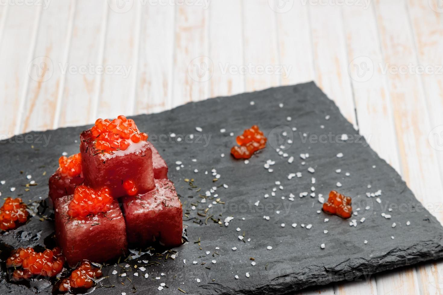 Tuna sashimi dipped in soy sauce with salmon roe, thick salt and dill on slate stone. Raw fish in traditional Japanese style. Horizontal image. photo