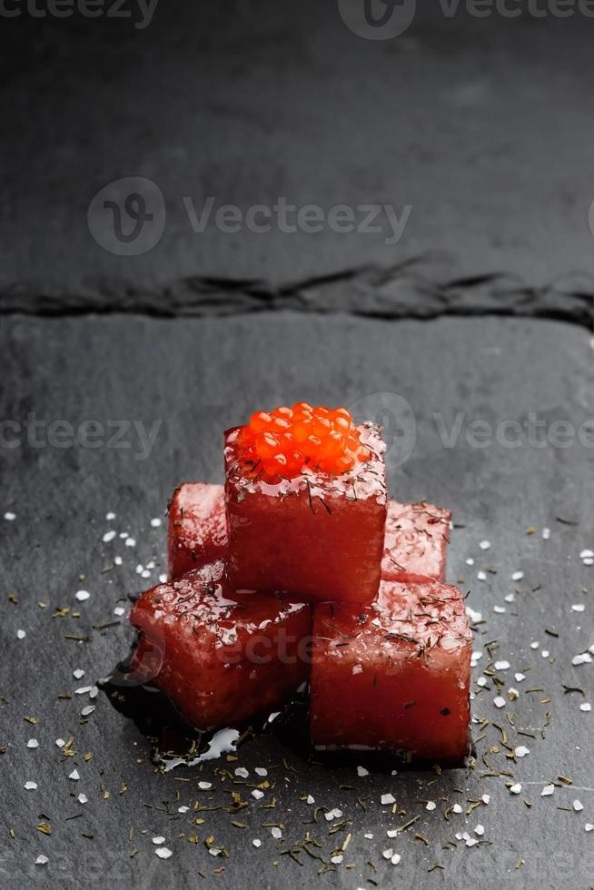 Tuna sashimi dipped in soy sauce with salmon roe, thick salt and dill on slate stone. Raw fish in traditional Japanese style. Vertical image. photo
