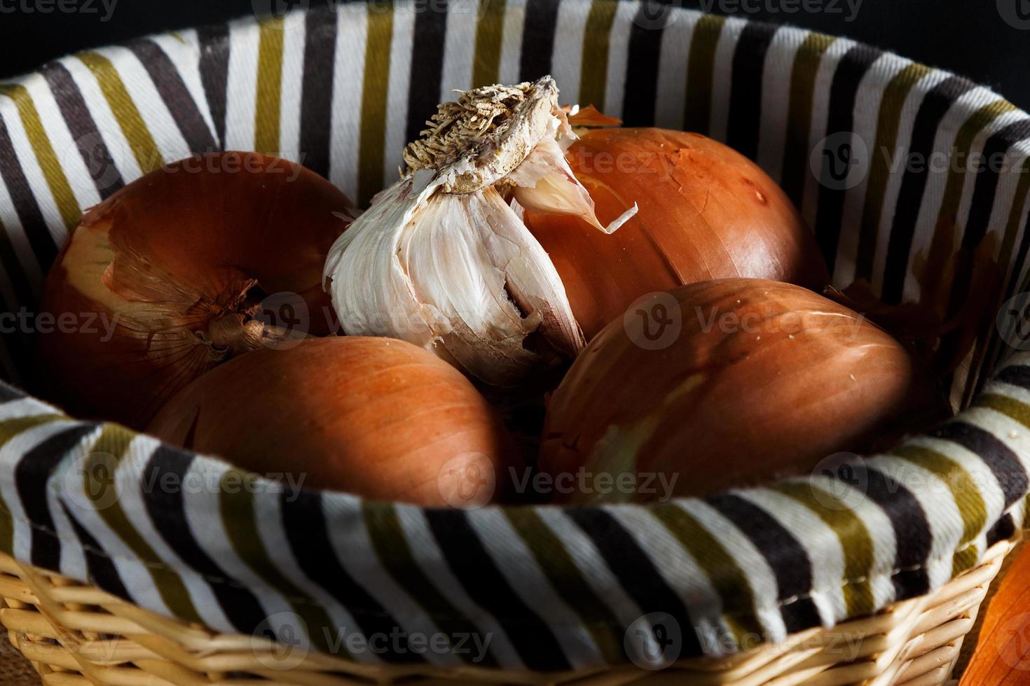 cebollas y cabeza de ajo en una cesta de mimbre visto de cerca. estilo rústico imagen horizontal foto