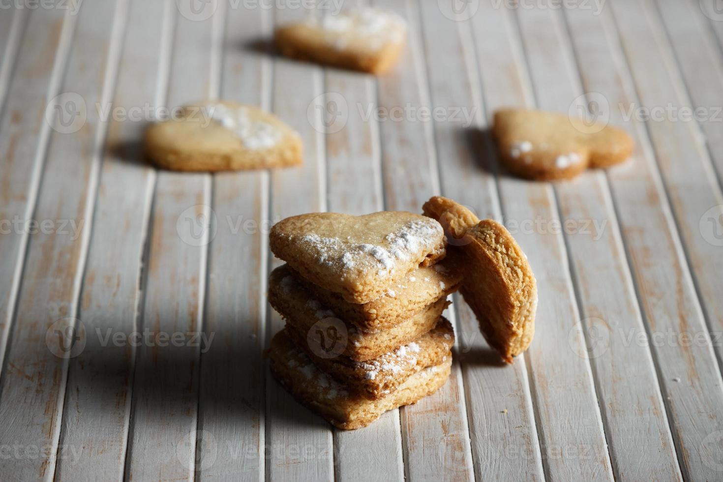 Delicious home-made heart-shaped cookies sprinkled with icing sugar in a wooden board. Horizontal image. Dark moody style. photo