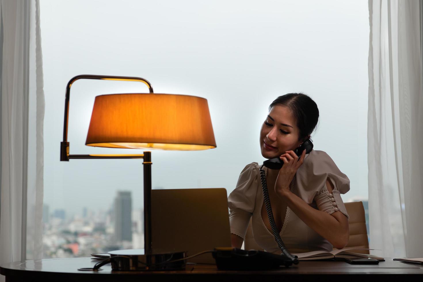 A young businesswoman monitors and keeps track of tasks in his office with a cityscape in the background of his desk. photo