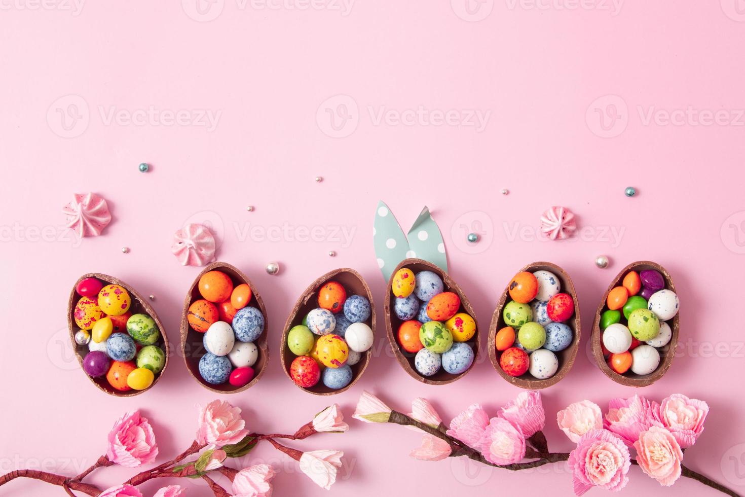 Chocolate easter eggs and decor flat lay for kids easter hunt egg concept on pink background. Sweets in the shape of an egg photo