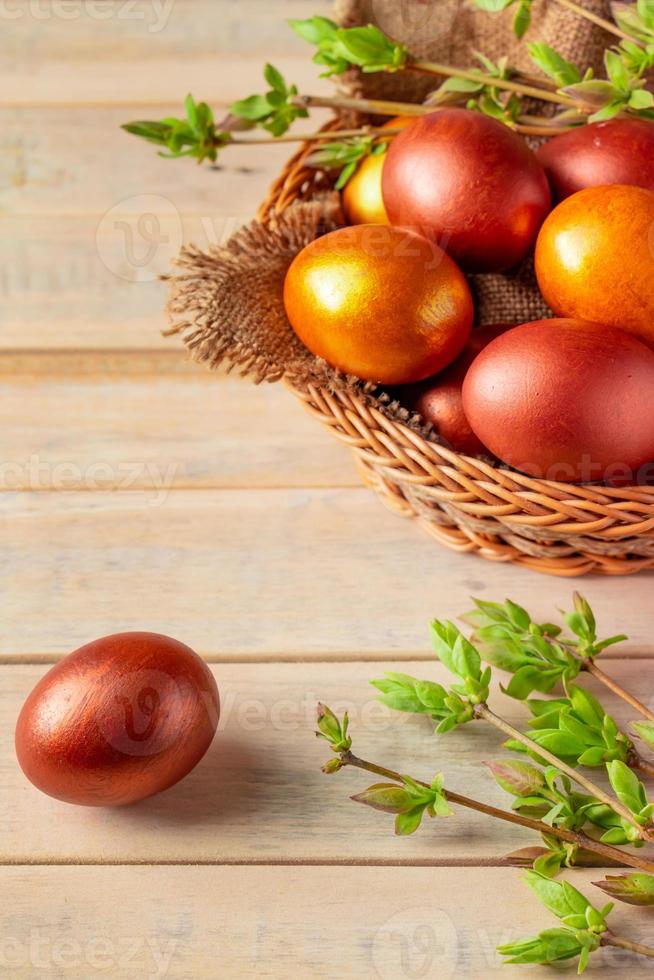 Golden Easter eggs in a wicker basket on a wooden background. photo