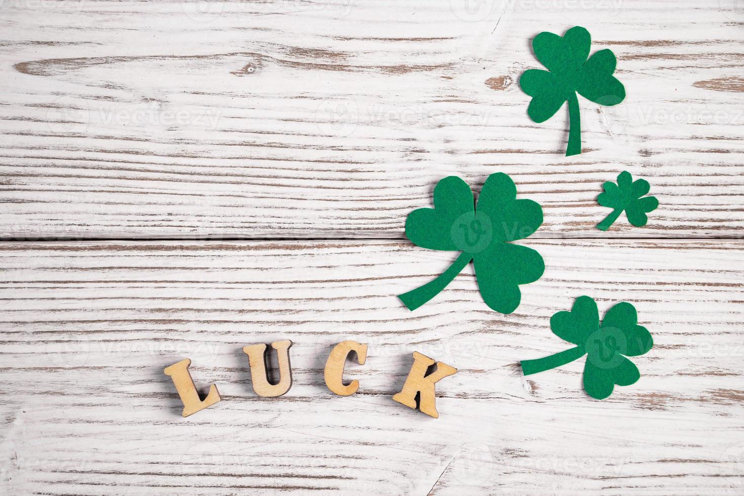 Word luck and shamrock clover leaves on a white wooden background. Happy St. Patrick's Day. photo
