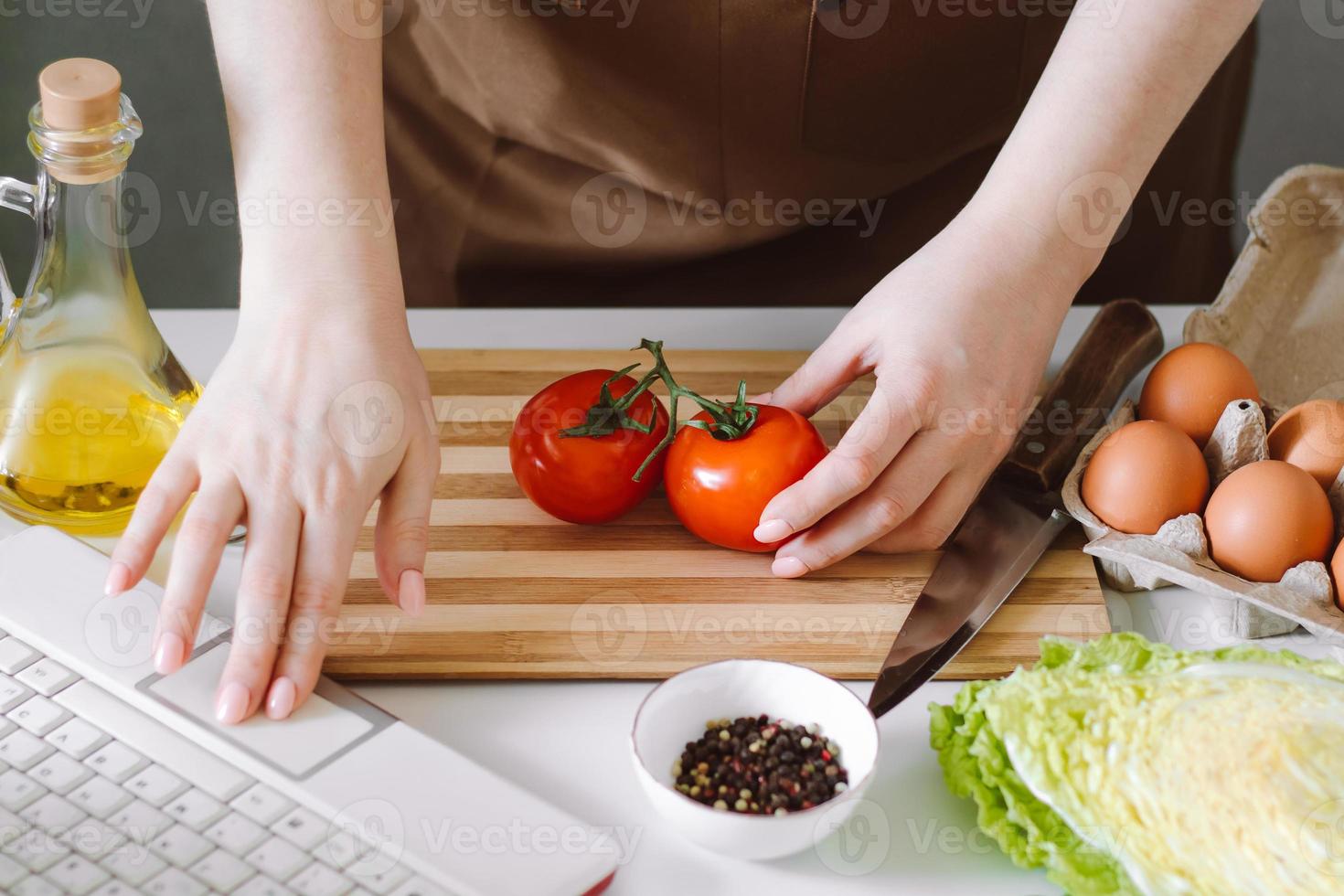 Woman blogger preparing diet vegetable salad. Online cooking lessons, using a laptop in the kitchen. photo