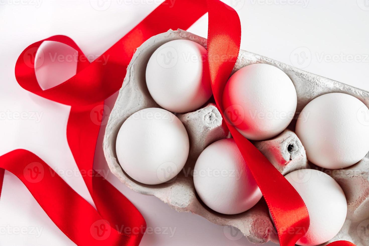 Easter eggs in a cardboard box with a red festive ribbon on a white background. photo