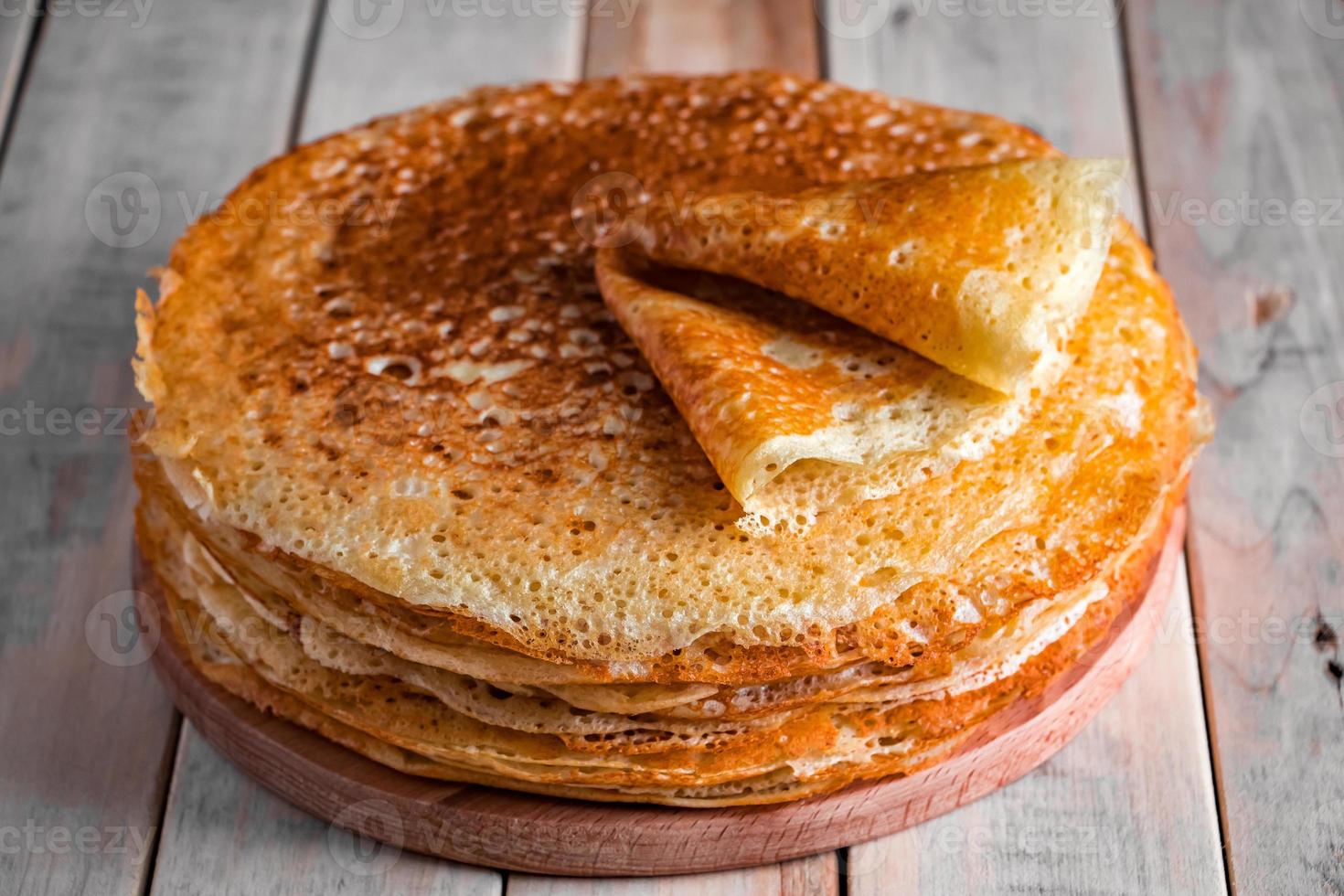 A stack of crepes on a wooden background. Russian food for the holiday Maslenitsa. photo