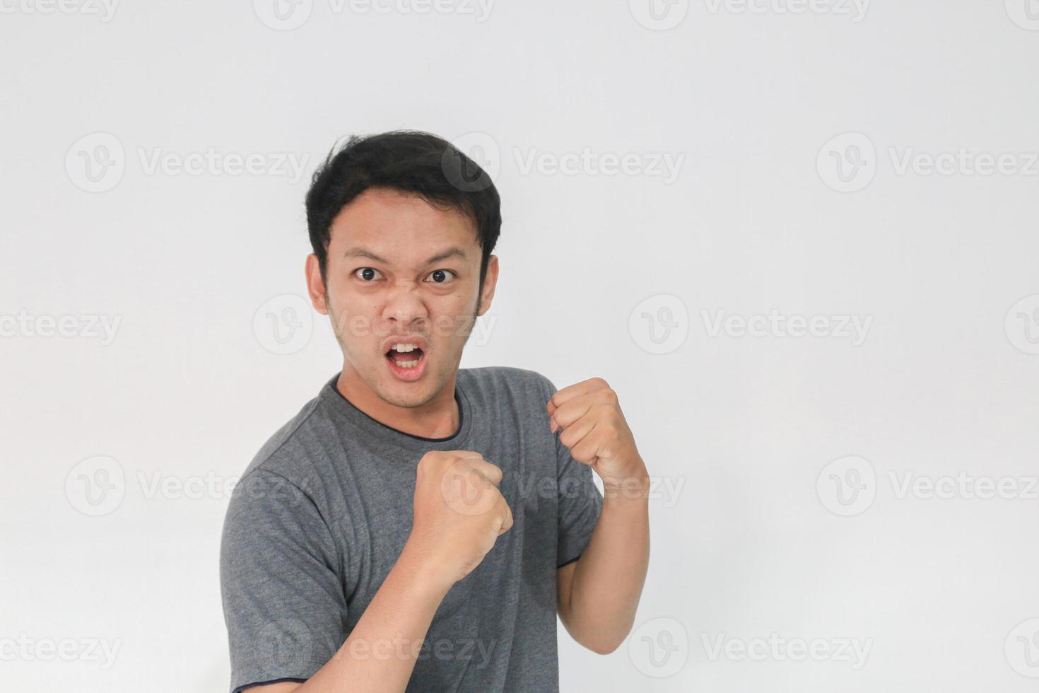 Angry and hate face of young Asian man in gray t-shirt with angry hand gesture photo