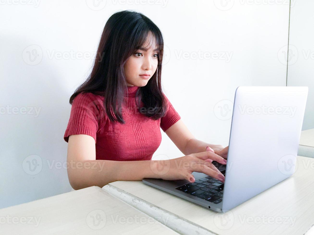 Asian beautiful girl serious or thinking in the front of laptop on the isolated white background photo