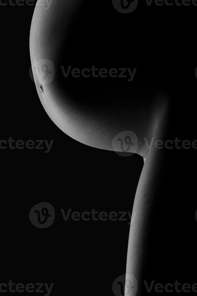 belly of a pregnant woman on a dark background photo