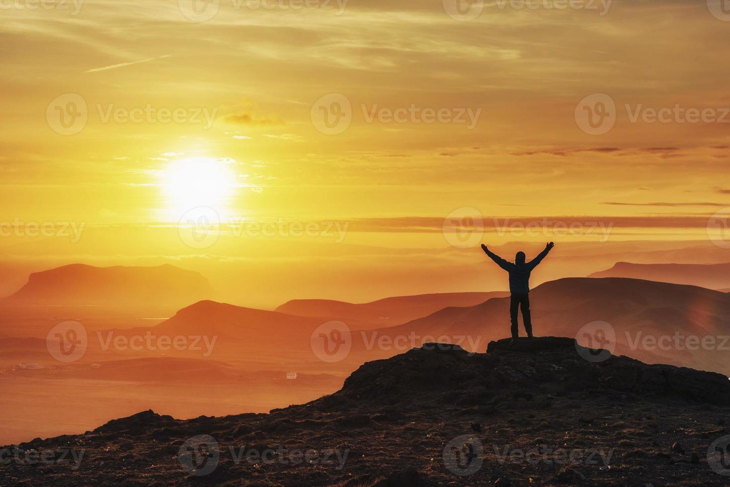 Happy man standing on a cliff at sunset photo