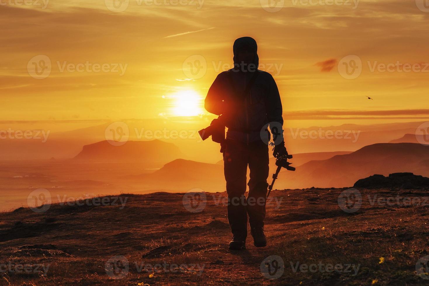 Happy man standing on a cliff at sunset photo