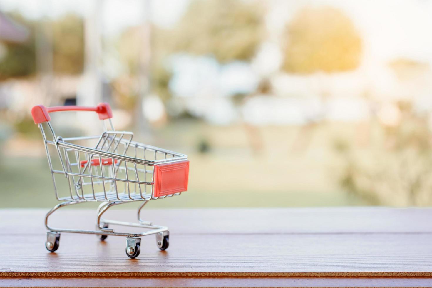 Shopping concept - empty shopping cart or trolley on brown wood table. online shopping consumers can shop from home and delivery service. with copy space photo
