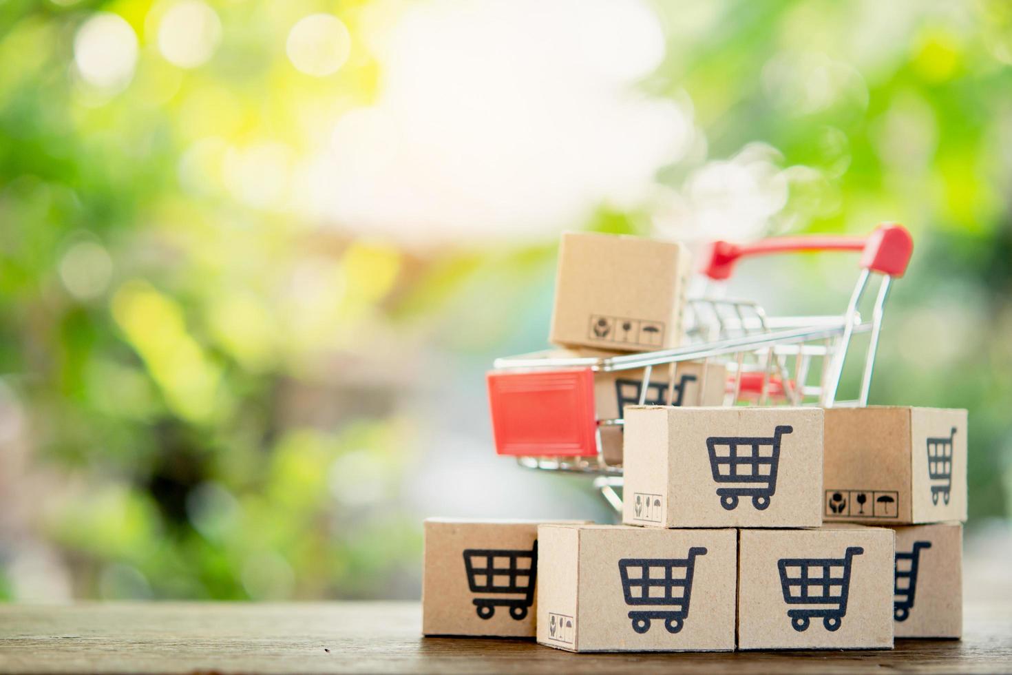 Shopping concept - Shopping cart or trolley and Paper cartons or parcel with a shopping cart logo on wood table. online shopping consumers can shop from home and delivery service. with copy space photo