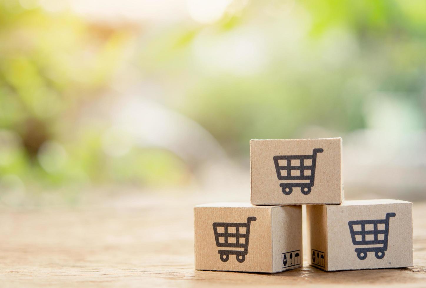 compras en línea: cajas de papel o paquetes con un logotipo de carrito de compras y crédito en la parte superior de la mesa de madera con espacio para copiar. servicio de compra en la web online y ofrece servicio a domicilio. foto