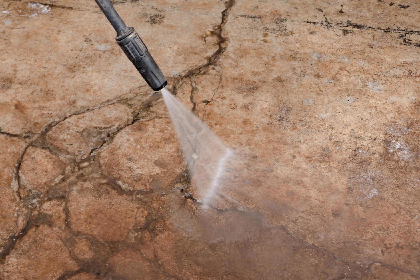 Worker cleaning dirty floor with high pressure washer photo